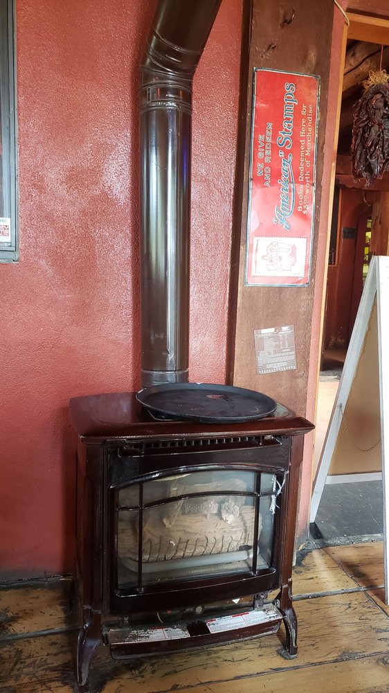 Cast-iron wood stove warming the dining room beside a vintage sign