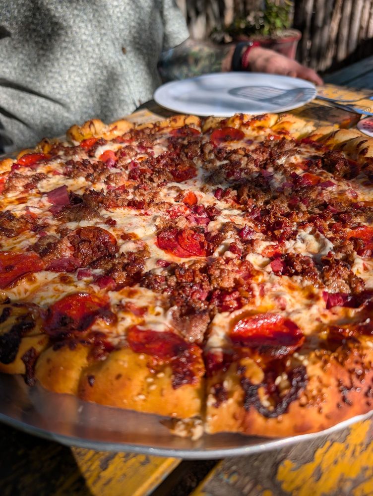 Loaded meat pizza with pepperoni, sausage and ham on a sesame crust