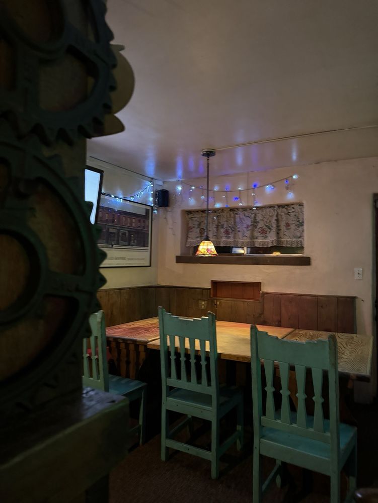 Adobe dining room with turquoise wood chairs and string lights