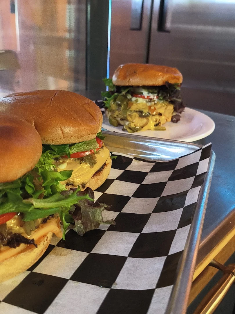 Green chile cheeseburgers stacked with lettuce and tomato on checkered paper
